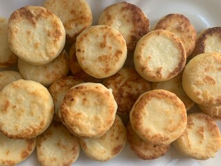 Cottage cheese and syrniki in large quantities. Delicious breakfast, golden cheesecakes served with powder. Caloric food, healthy ingredients
