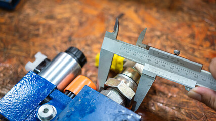Using Vernier caliper to measure the machinery part's dimension on workbench table. Industrial...