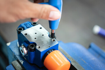 Action of a worker is using hexagonal spanner to tightening the screw of an electronic equipment during repairing. Industrial working scene photo, close-up and selective focus. - obrazy, fototapety, plakaty