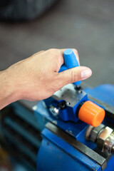 Action of a worker is using hexagonal spanner to tightening the screw of an electronic equipment during repairing. Industrial working scene photo, close-up and selective focus.