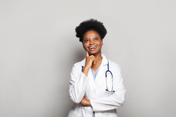 Attractive black woman doctor in white uniform looking up on white banner background