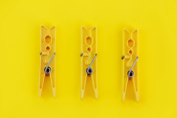 plastic clothespins for fastening laundry, on a yellow background - obrazy, fototapety, plakaty