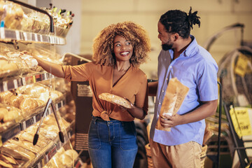 Beautiful young couple is choosing baking and smiling while doing shopping at the supermarket