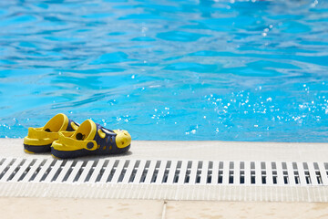 Obraz premium Beautiful, yellow, children slippers are standing by the pool. Safety near the pool.