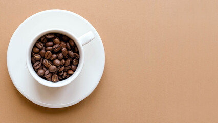 Obraz na płótnie Canvas A cup of coffee with a saucer and coffee beans on a brown solid background with space for text