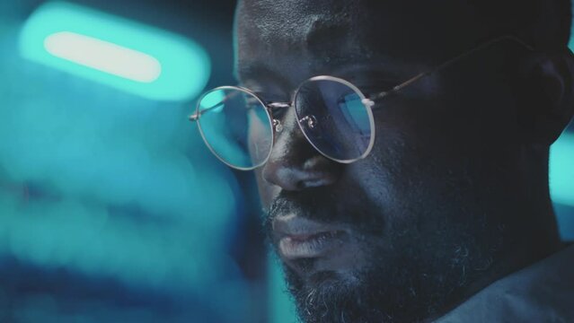 Close up view of face of African American data center specialist working in dark server room