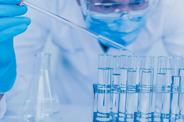 Concept of chemical, scientific experiment, monkeypox virus. Closeup, copy space on right. Chemistry experiments in science labs. Drop chemical matter into test tube place on desk. Blurred background