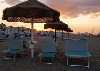 View over empty sunbeds at sandy beach of Rivazzurra, Rimini, Italy on sunset