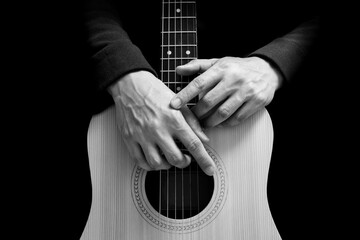 black and white male guitarist hands on acoustic guitar body, isolated on black. music background
