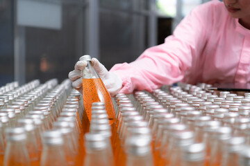 Product quality control staff at the fruit juice production line Perform product quality checks To ensure that the products produced are of good quality