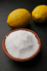 Coarse salt in a bowl and lemon on black background 