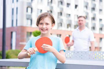 the boy holds a racket and a ball for ping pong and table tennis in his hand, is about to start the...