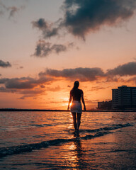 a woman walking along Waikiki Beach in Honolulu Hawaii during sunset