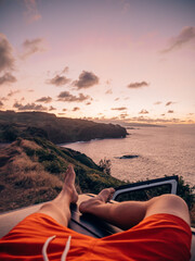 a tourist in Maui, Hawaii chilling on the top of his car overlooking the coast during sunset
