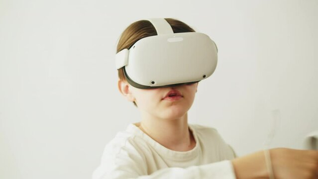 Boy using virtual reality glasses with controllers, playing video games, child gamer wearing new generation gaming headset for entertainment and education, future technology concept.