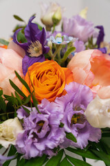 Close up of a Mixed Summer Bouquet with Orange Roses, purple and blue flowers, white background.
