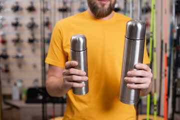 Choosing thermoses in a store, person choosing a thermos in a fishing shop