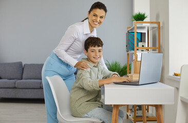Parent helps child do homework or log into online class. School teacher helping kid learn ICT...