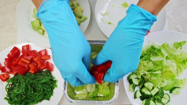 Chef make fresh vegetable salad close up top down view. Woman cook hands put ingredients slices in disposable container. Cooking, preparing in professional restaurant. Healthy food delivery. 4K shot