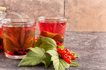 Tea made from berries and leaves of black and red currants in two transparent glasses on a dark background. Space for text. A drink rich in vitamin C. A useful alternative for colds.
