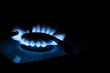 The blue flame of the gas stove burner on a black background. The concept of energy risis. Selective focus.