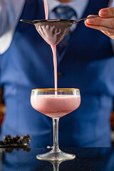 Straining a Pink Gin Cocktail
