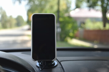 Smartphone in a holder on the dashboard of a car.