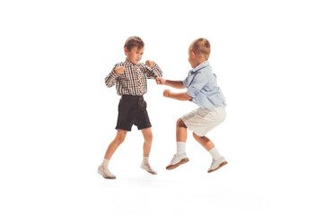 Fototapeta na wymiar Portrait of two little boys, children playing together, having fun isolated over white studio background