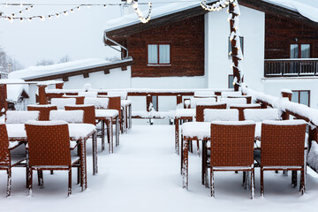 Empty snow-covered tables of a street cafe. Open air cafe under the snow