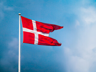 Danish flag blows in the wind infront of blue sky