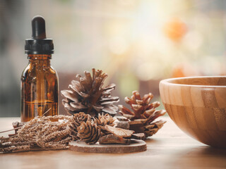 Dark glass bottle with essential oil blend with cinnamon, dried citrus slice, pine twigs, cones and wooden background. Nature home deodorants and warm toned.