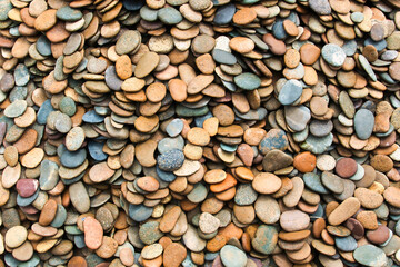 Pattern of smooth, rounded river stones. Background of smooth stones in soft colours
