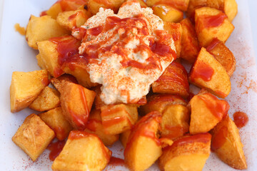 baked potato with garlic sauce aioli and tomato ketchup on square plate with human hands close up photo
