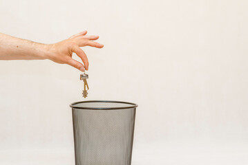 The home keys is thrown into the trash,can for disposal and recycling.White,gray background,selective focus,copy space.