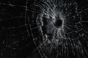 Bullet hole in a glass on the black background.closeup.