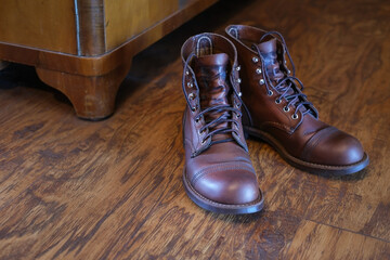 pair of  rough leather boots on wooden floor on background of wooden vintage cupboard