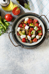 Healthy vegetarian diet food. Salad with grill eggplants, tomatoes and feta cheese on a gray stone tabletop. View from above. Copy space.