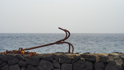 old anchor on a wall next to the ocean or sea