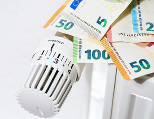 Radiator battery heating system with thermostatic temperature control on low and euro banknotes. expensive heating bills and rising energy bill prices in Europe. Winter cold season and energy crisis