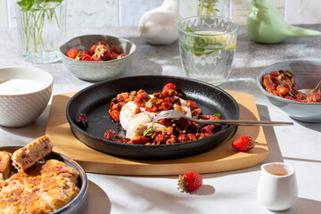 Baked camembert cheese served with berries, nuts and herbs sauce on gray table on sunny day.