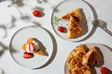 British scones with cream and strawberry.  Homemade strawberry scones cut in triangles on gray table on sunny day. Traditional english buns. Top view.