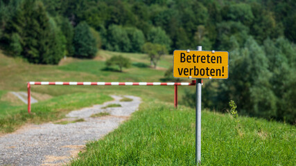Betreten verboten Schild und Schranke mitten in einer grünen Wiesenlandschaft