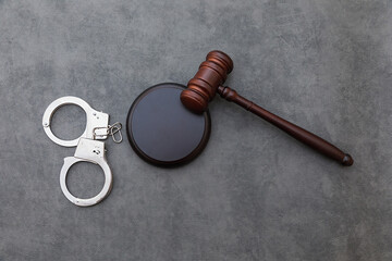 Law theme. Court of law trial in session. Judge gavel handcuffs on grey table in lawyer office or...
