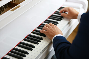 Fototapeta na wymiar Musician playing on beautiful white piano, hands and keys closeup 