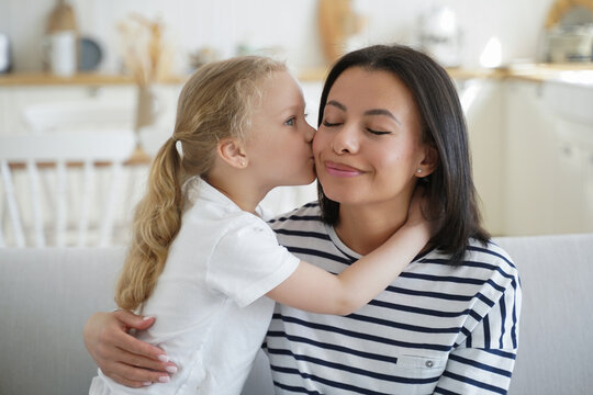Little kid girl foster daughter kiss cuddle mother at home. Happy motherhood, adoption of child