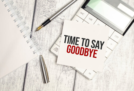 Text time to say goodbye on paper card and calculator on wooden background