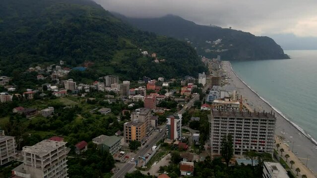 Drone flying over the city of Gonio on a rainy day. Fog shrouds the mountains, lush greenery grows on the slopes.