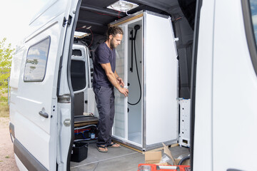 Man installing a shower room inside a camper van © photoschmidt