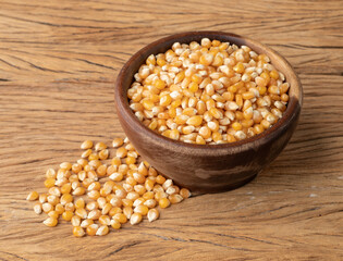 Dried corn or popcorn grains in a bowl over wooden table