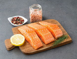 Raw salmon slices with seasonings over wooden board